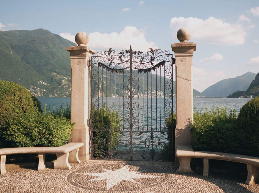 A wrought iron style gate closed across an opening in a fence.