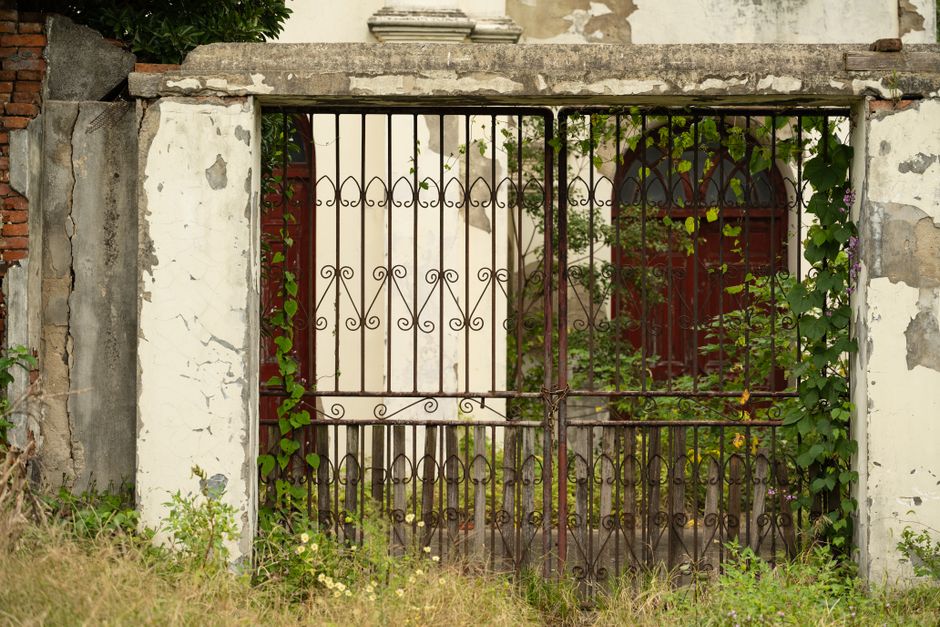 A painted metal gate beside a garden path.
