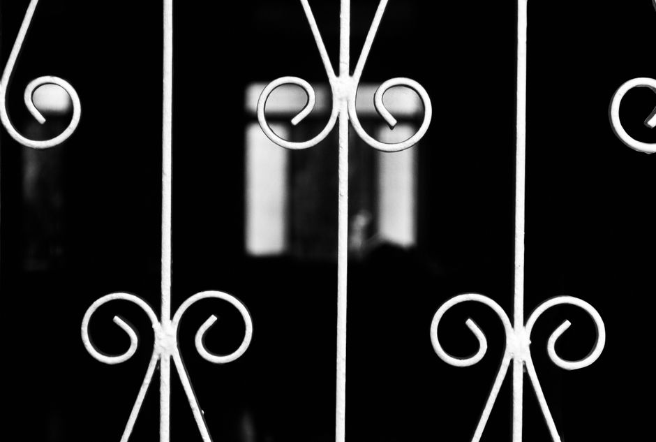 A black metal gate with decorative pickets set in a fence line.