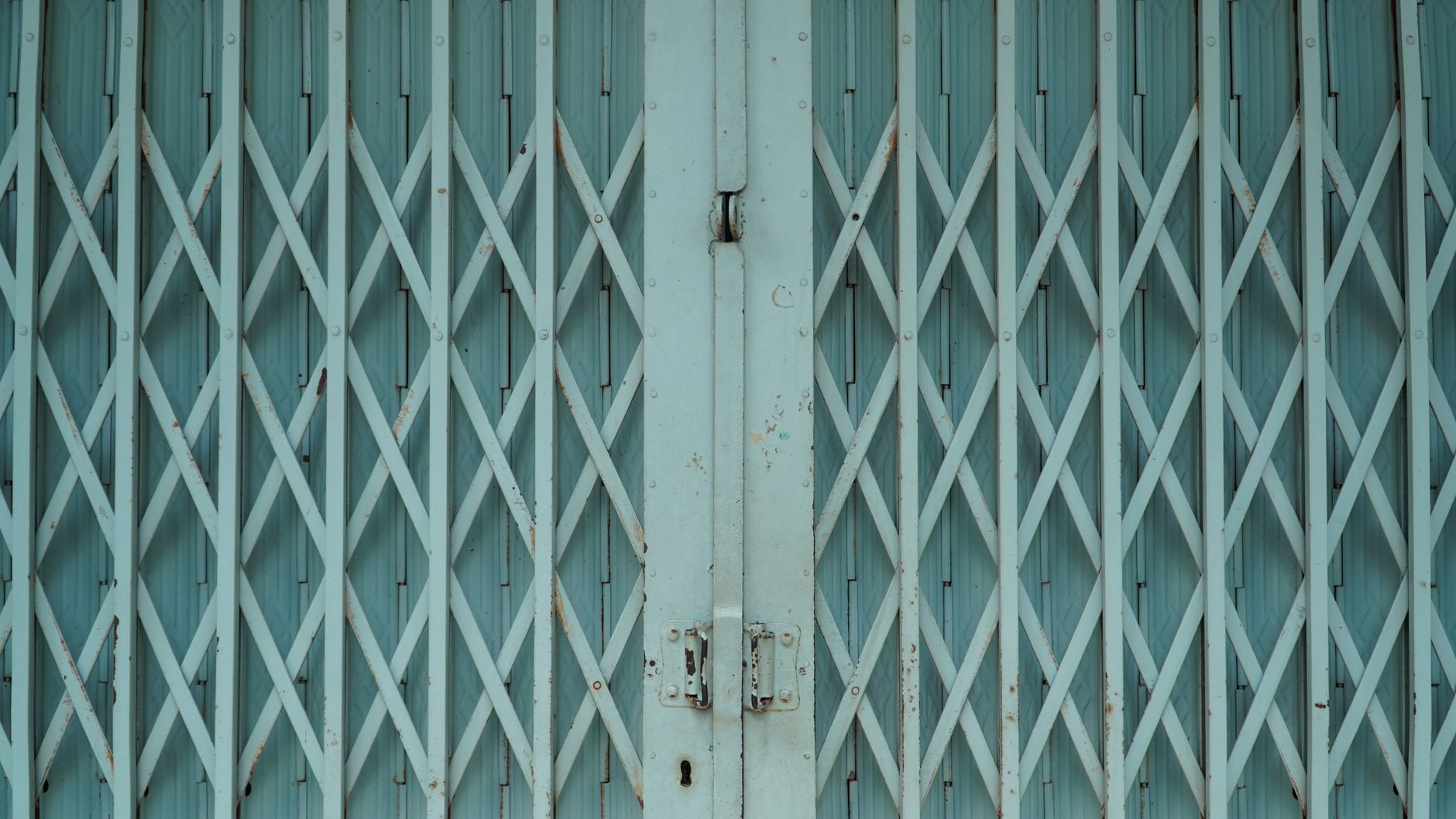 Detailed view of a light blue metal accordion gate with rust marks and texture in Austin, TX