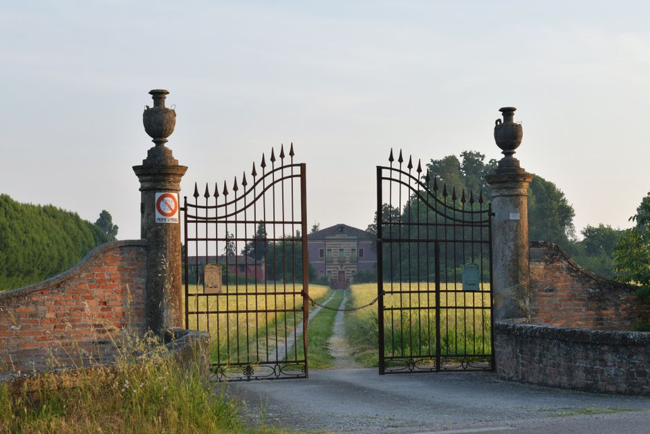 An iron gate hung between two posts at a yard entrance.