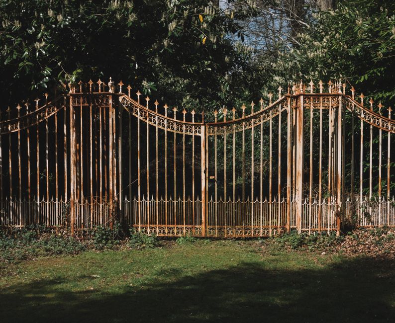 A painted metal gate beside a garden path.