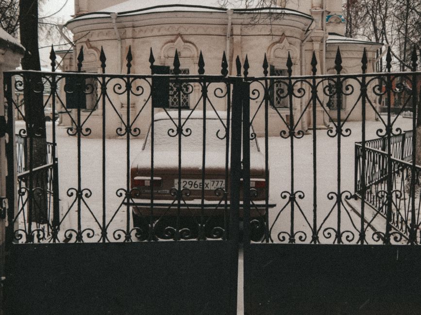 An iron gate hung between two posts at a yard entrance.